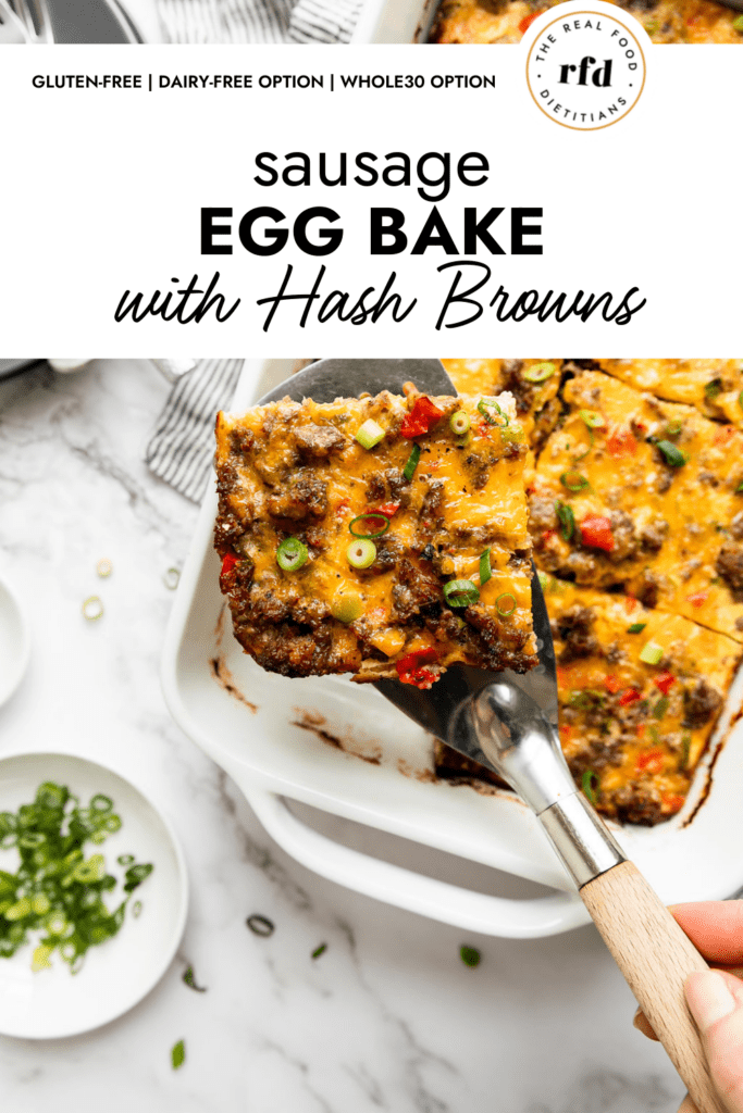 A serving spatula lifting a piece of sausage egg bake with hash browns from a white casserole dish.