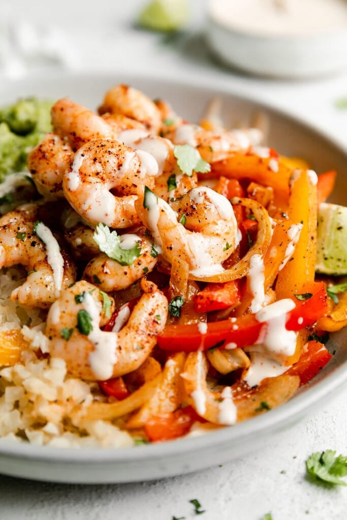 Close up view of shrimp fajita bowls topped with homemade ranch dressing.