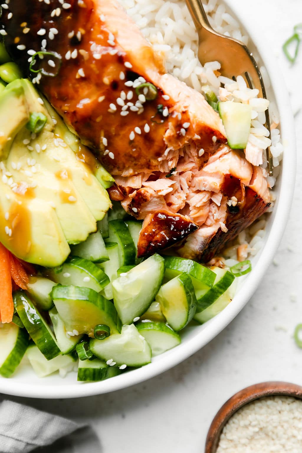 Close up view of Teriyaki Salmon Bowl served in white bowl, the teriyaki salmon filet flaking apart with perfect broiling. 