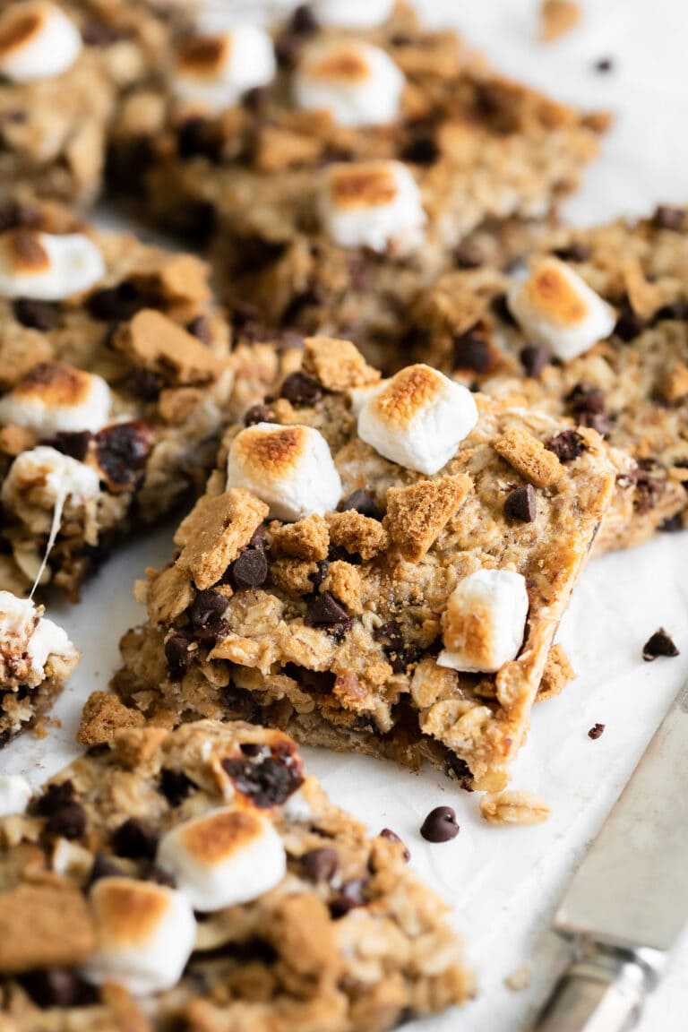 Close up view of squares of chewy s'mores granola bars topped with mini marshmallows.