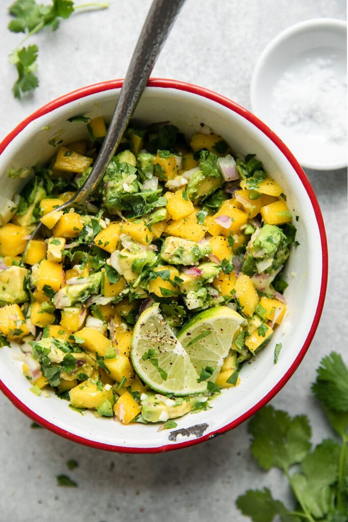 Overhead view of mango avocado salsa in a white bowl with a red rim.