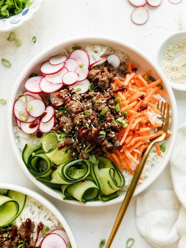 Overhead view korean-inspired ground beef bowl served over rice in white bowl.