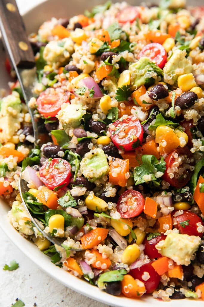 Close up view Tex-Mex Quinoa Salad in white bowl with spoon in salad.