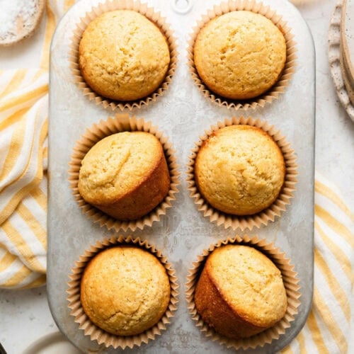Overhead view of a muffin tin filled with homemade cornbread muffins in liners.