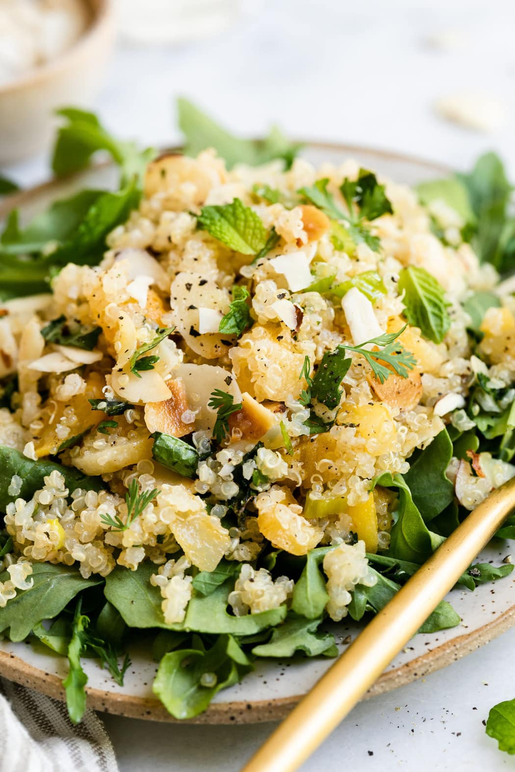 Close up view herbed quinoa pilaf plated on plate with mixed greens.