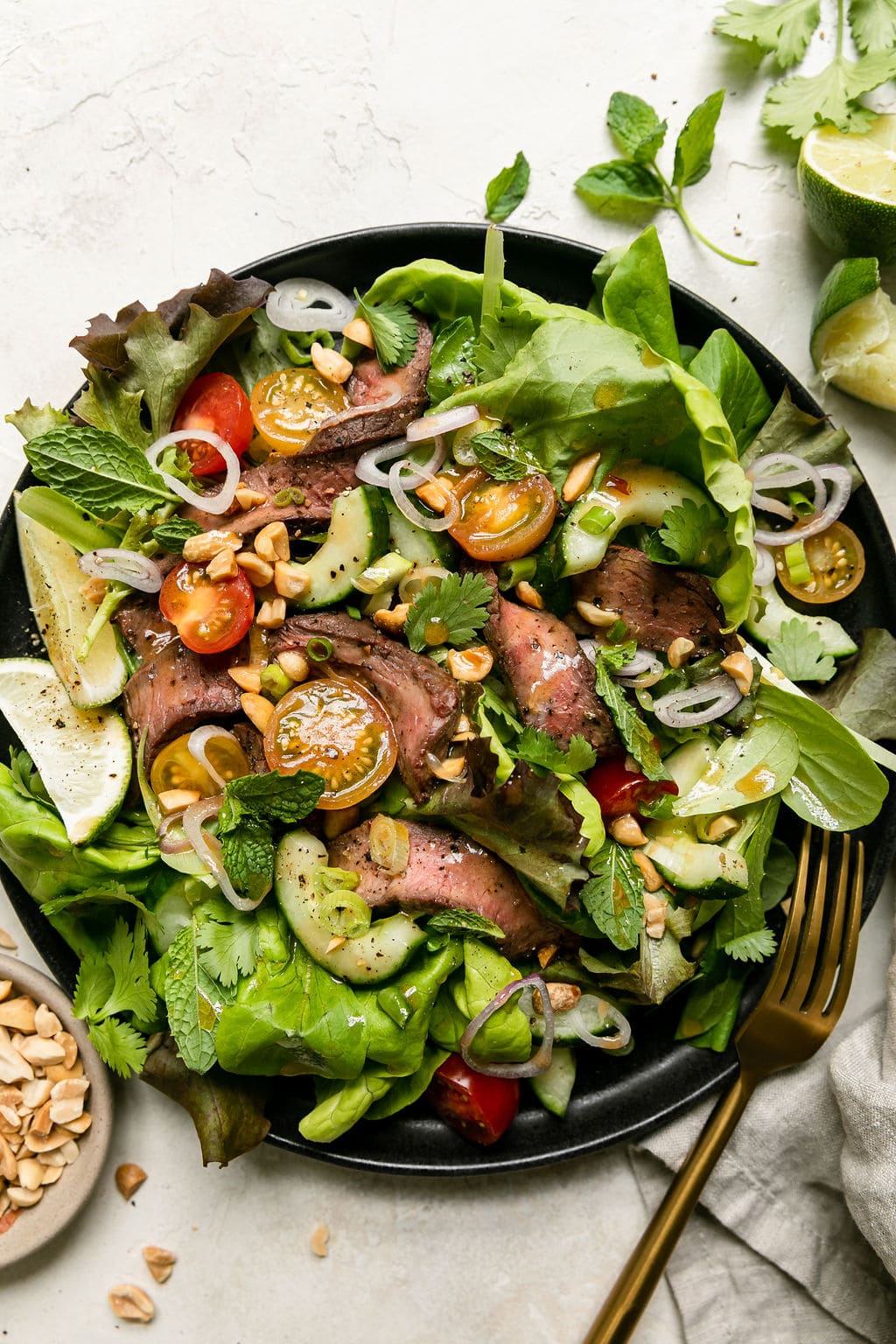 Thai steak salad with mixed greens served in black plate
