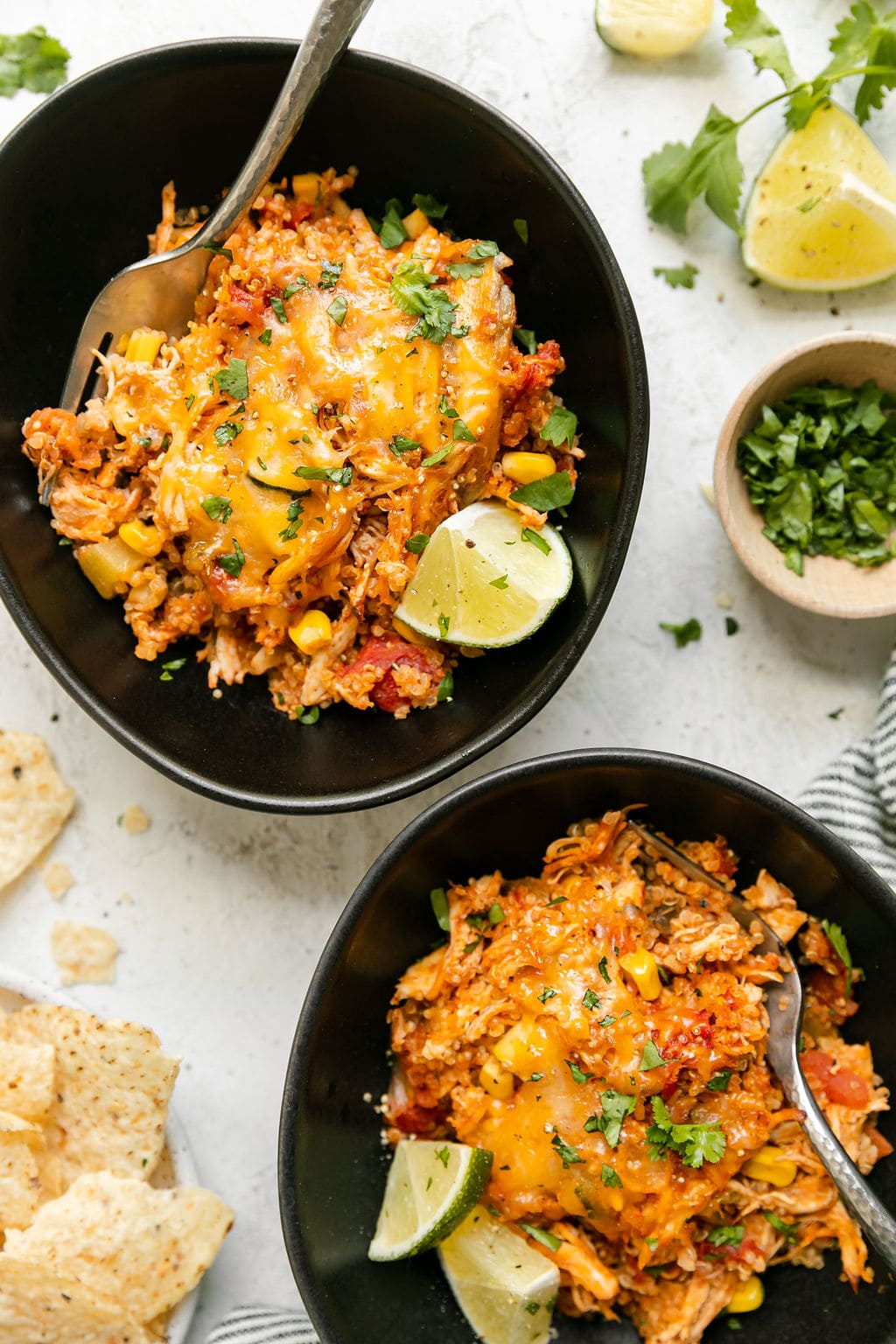 Two black bowls filled with chipotle quinoa casserole with chicken and melted cheese.