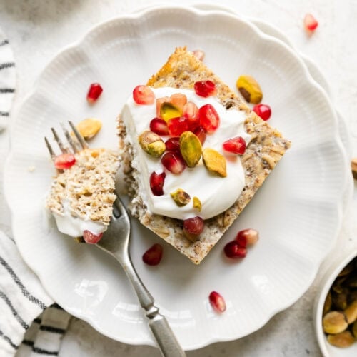 Overhead view serving of protein baked oatmeal on white plate, topped with Greek yogurt and fresh berries.