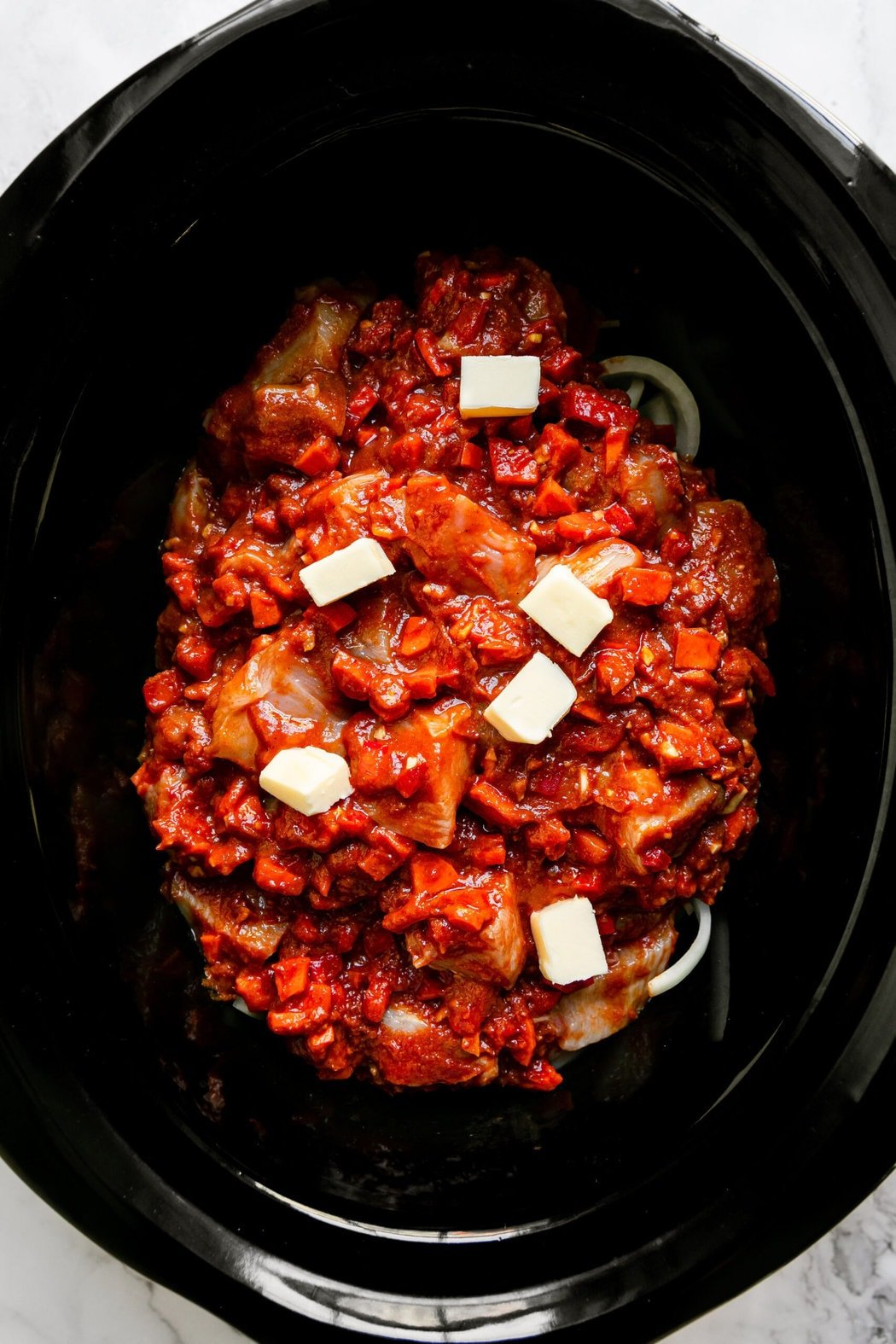 Overhead view of Butter Chicken ingredients in a crockpot ready for cooking. 