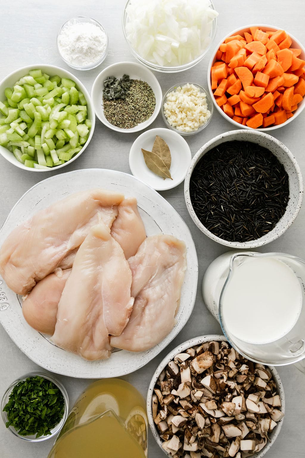 Overhead view all ingredients for slow cooker chicken wild rice soup arranged together in small bowls.