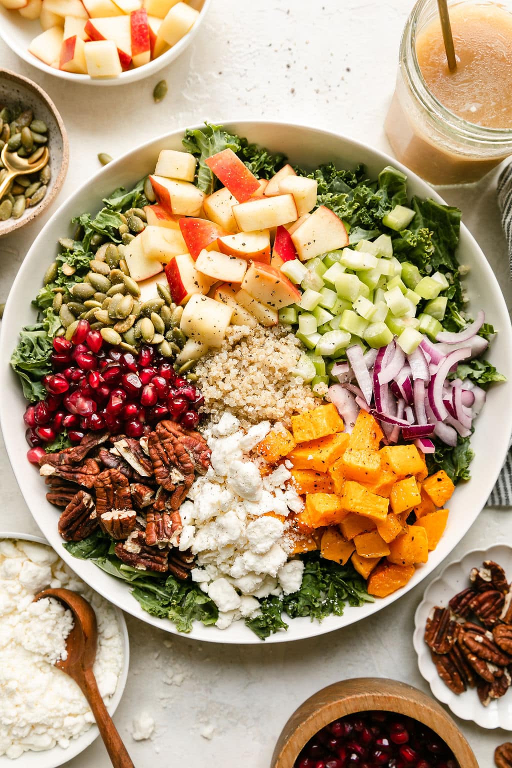 All ingredients for harvest salad sitting on top of massaged kale ready to be tossed together