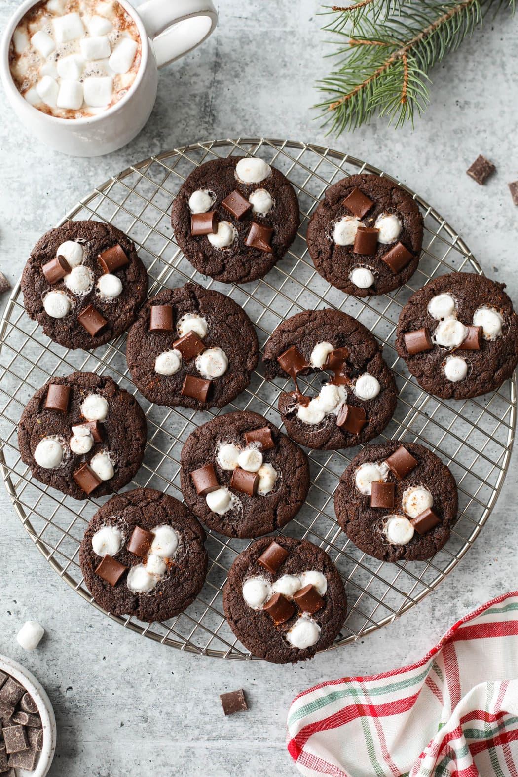 Overhead view wire cooling rack filled with Mexican hot chocolate cookies topped with melty mini marshmallows and chocolate chunks.
