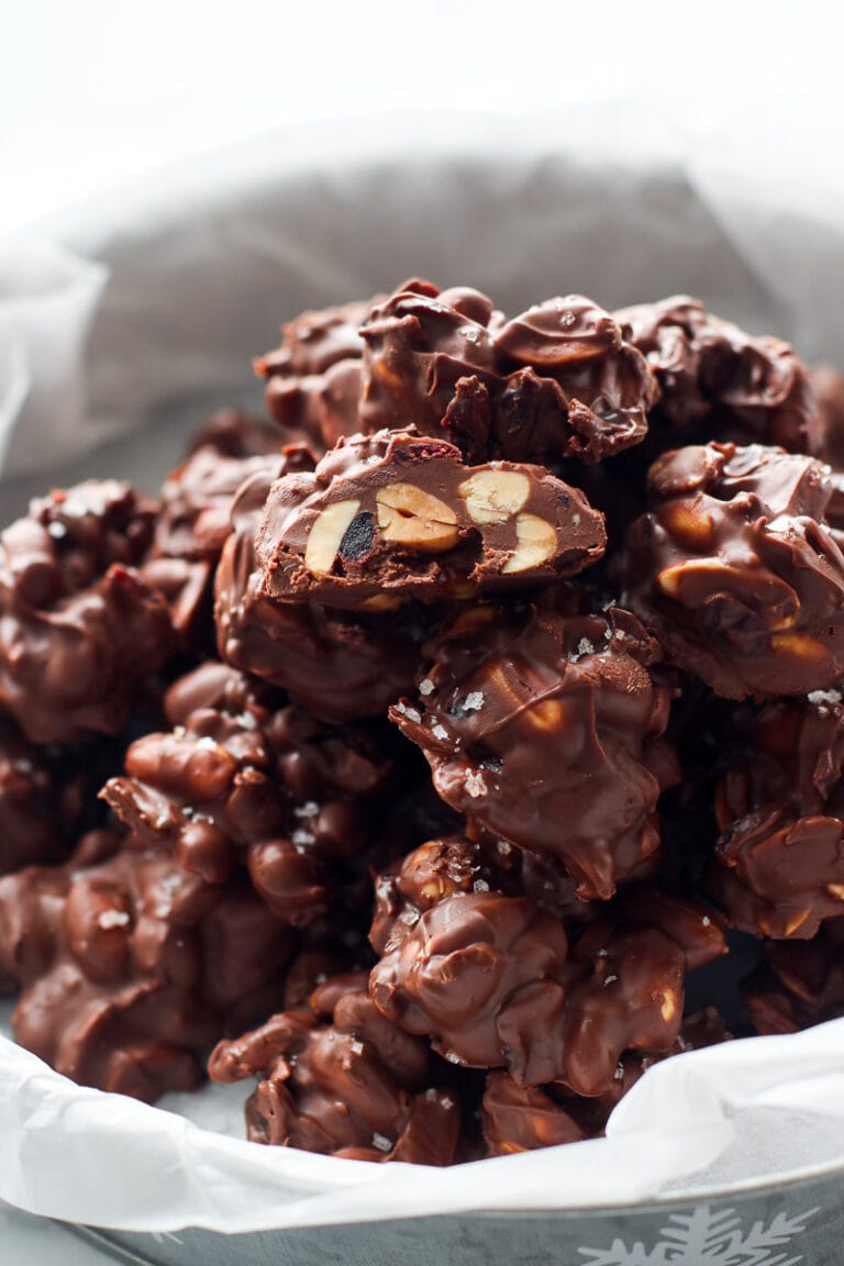 Close up view of a batch of chocolate peanut clusters topped with flakey sea salt.