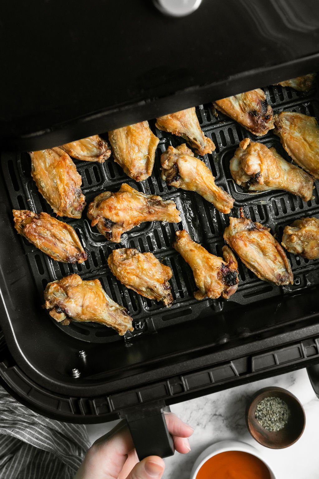 Cooked chicken wings in an air fryer basket.