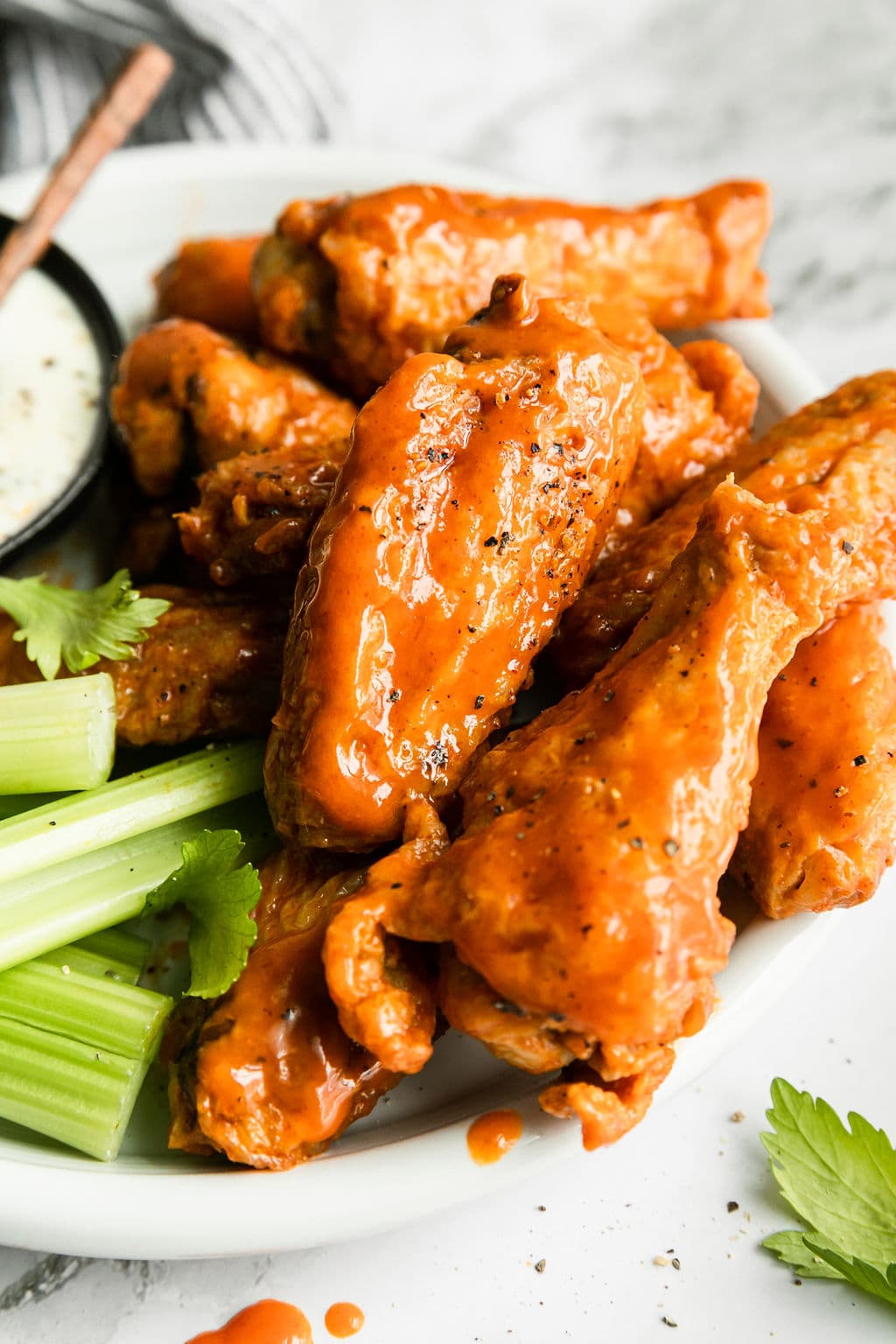 Close up view air fryer chicken wings coated in buffalo sauce.