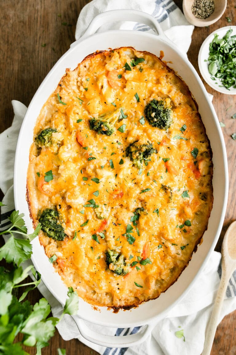 Close up view of a pan of cheesy chicken and rice casserole topped with melted cheese. 