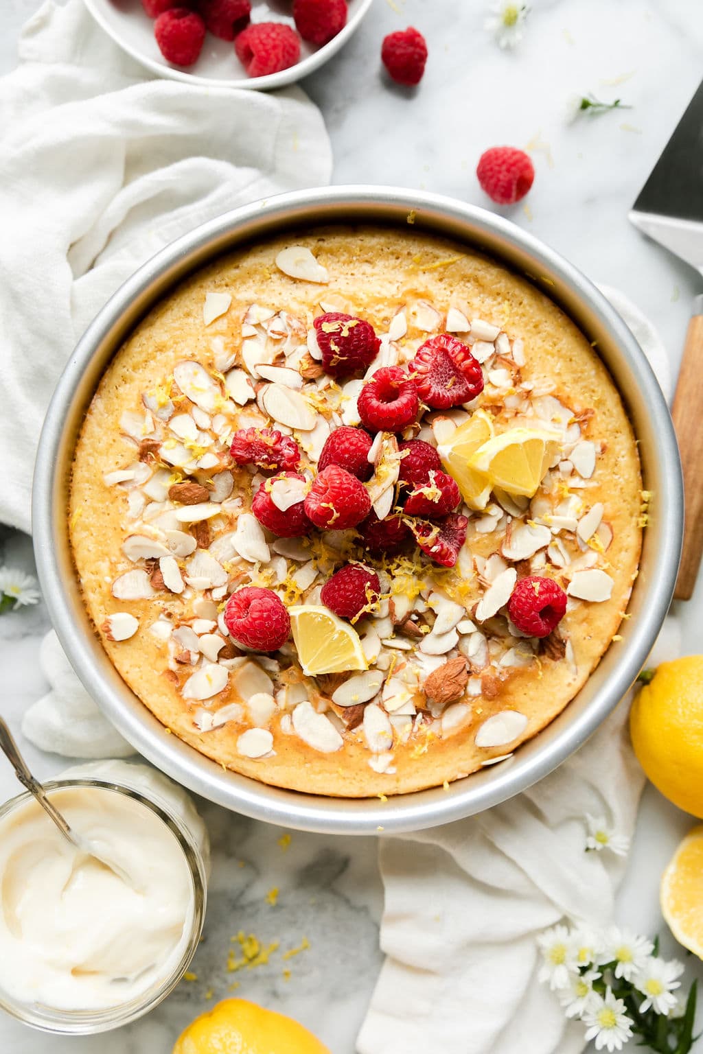 Whole Raspberry Coffee Cake with Lemon after being baked, topped with fresh raspberries and sliced almonds
