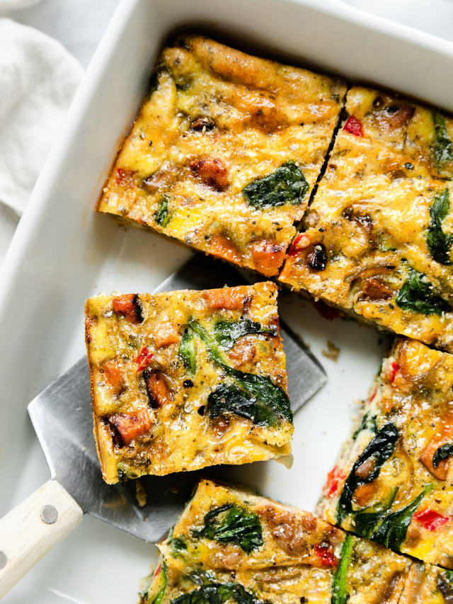 Serving of breakfast casserole being removed from white baking dish