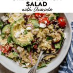 Overhead view stone bowl filled with Greek quinoa salad with artichoke hearts, avocado and tomatoes
