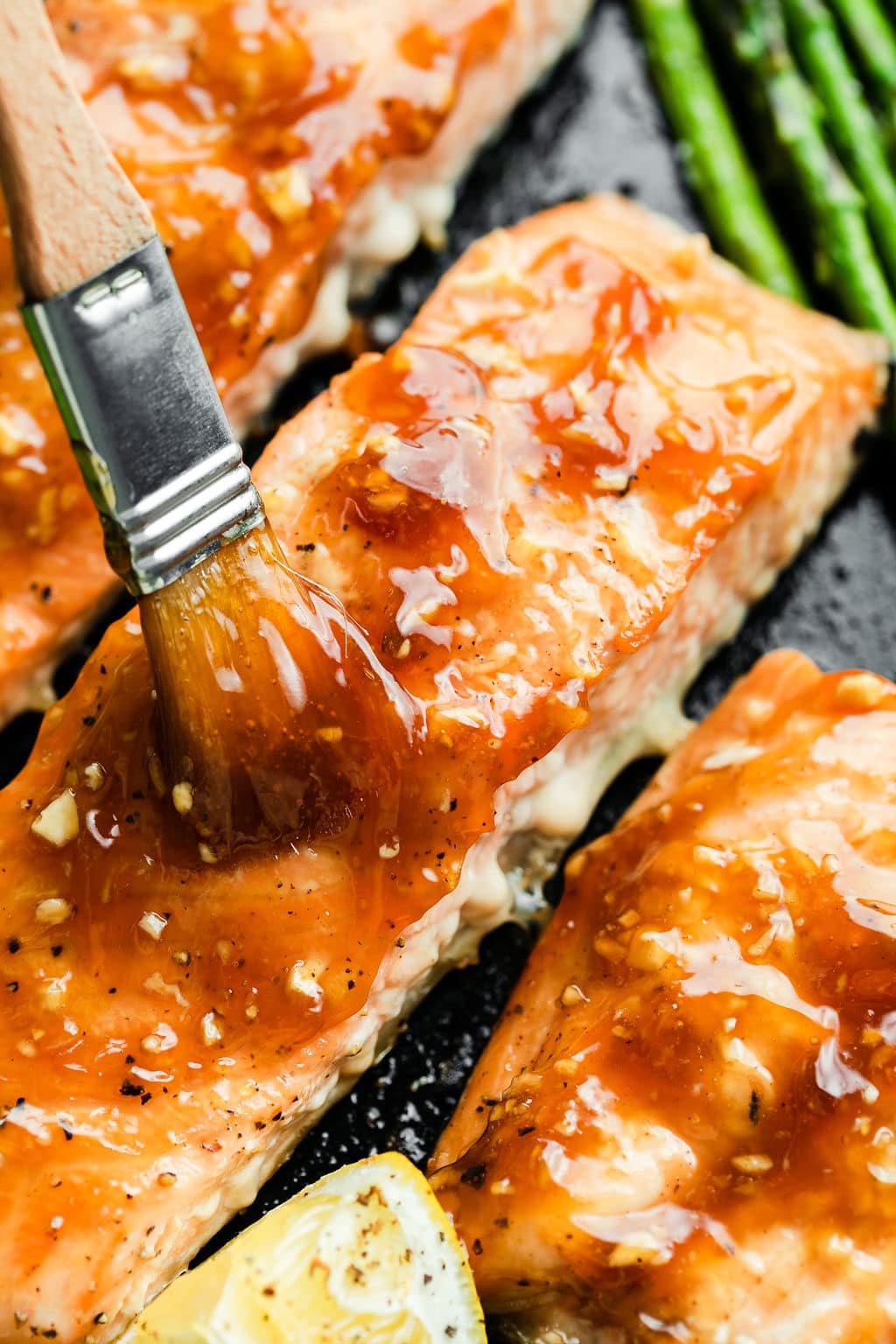 Small brush brushing honey garlic sauce on salmon filets.