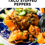 Side view taco stuffed bell pepper topped with melted cheddar cheese on blue plate