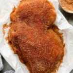 Pork loin roast rubbed down with easy rub placed on parchment paper ready to be grilled.