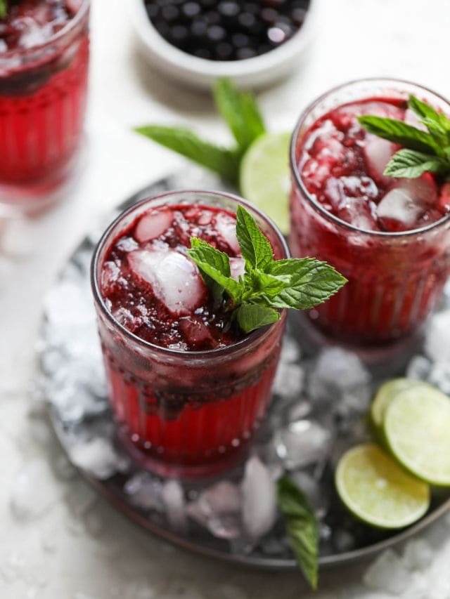 Overhead view tall glasses of blueberry mojito garnished with fresh mint