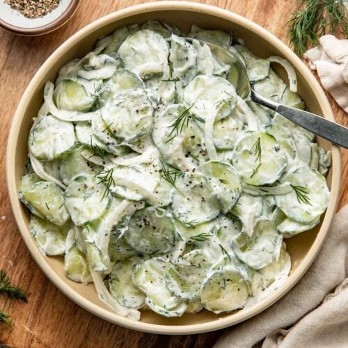 Overhead view of a bowl of Creamy Cucumber Salad topped with fresh dill.