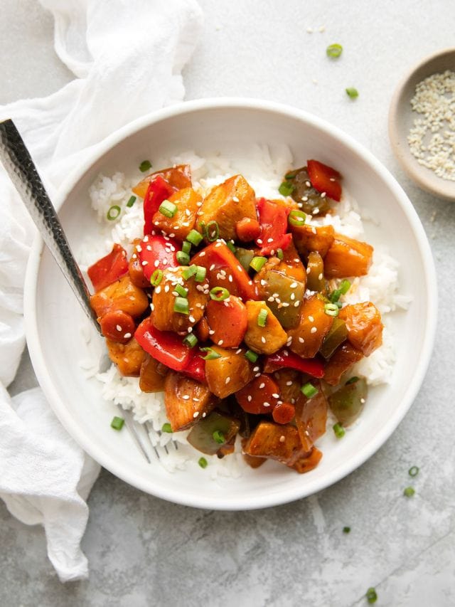 Overhead view white bowl filled with sweet and sour chicken served over rice