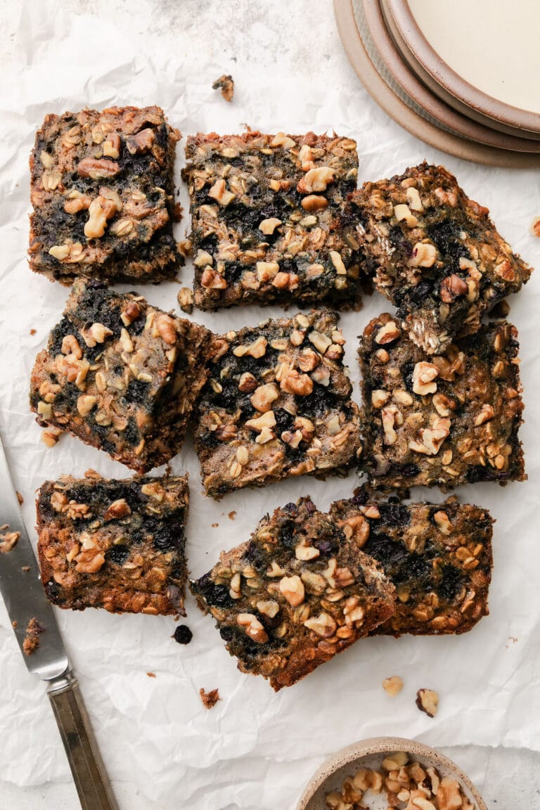 Overhead view of a batch of blueberry oatmeal breakfast bars cut into squares and topped with chopped walnuts. 