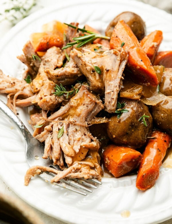 A plate of crock pot pork roast with carrots and potatoes.