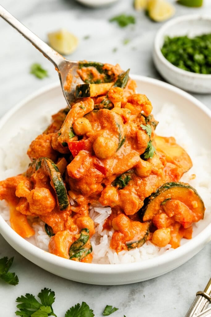 Spoonful of vegetarian tikka masala being spooned over bowl of rice