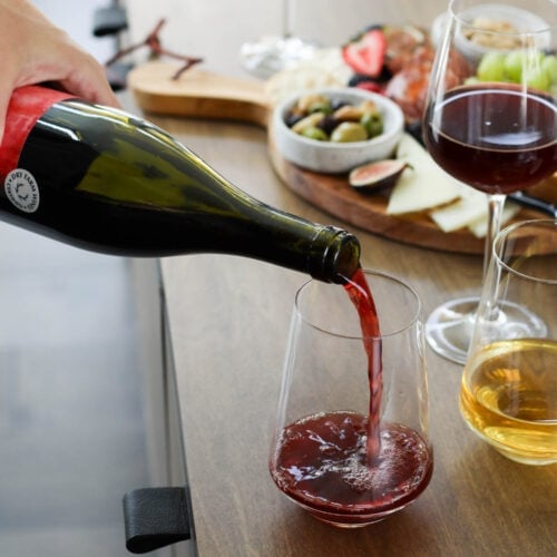 Red wine being poured into glass on wooden countertop