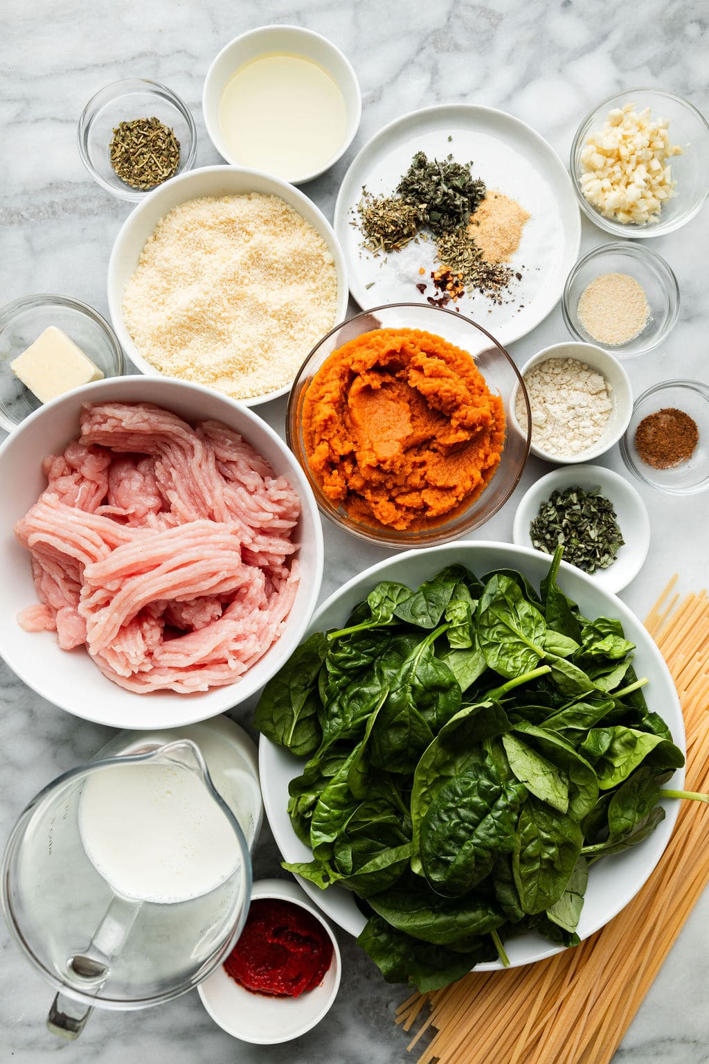 Overhead view all ingredients for pumpkin pasta with sausage arranged in smaller bowls