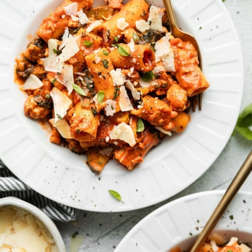 Overhead view rigatoni with Parmesan in white bowls