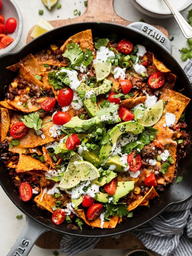 Overhead view cast iron skillet filled with Beef Skillet Enchiladas topped with avocado slices