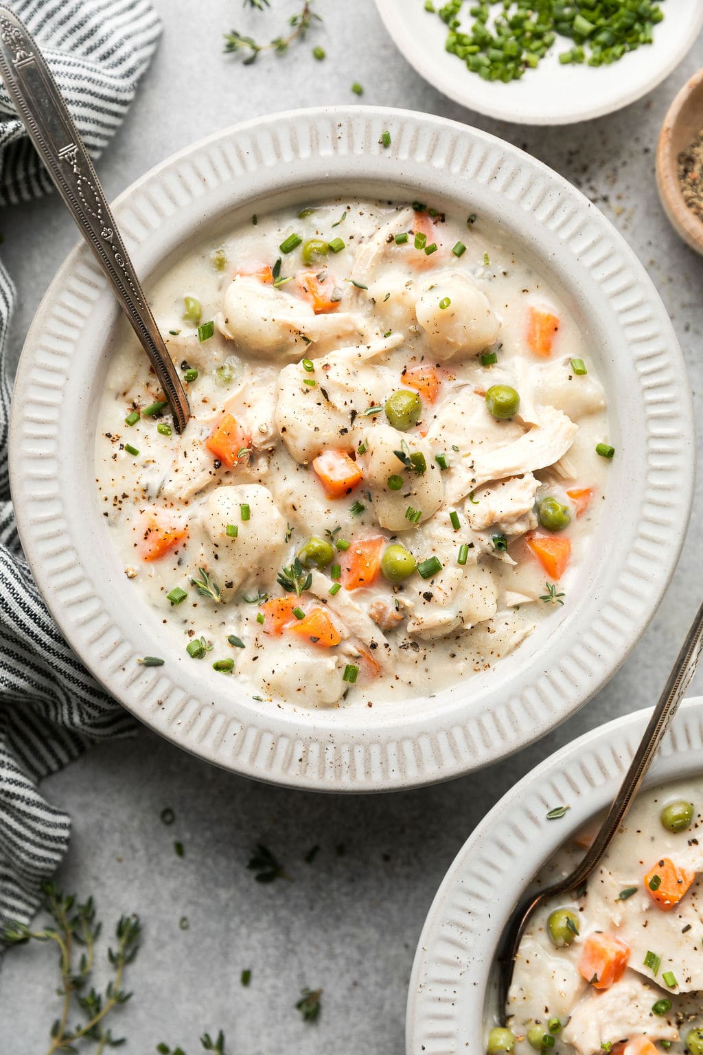 A bowl of yummy Chicken Dumpling soup garnishes with chopped herbs.
