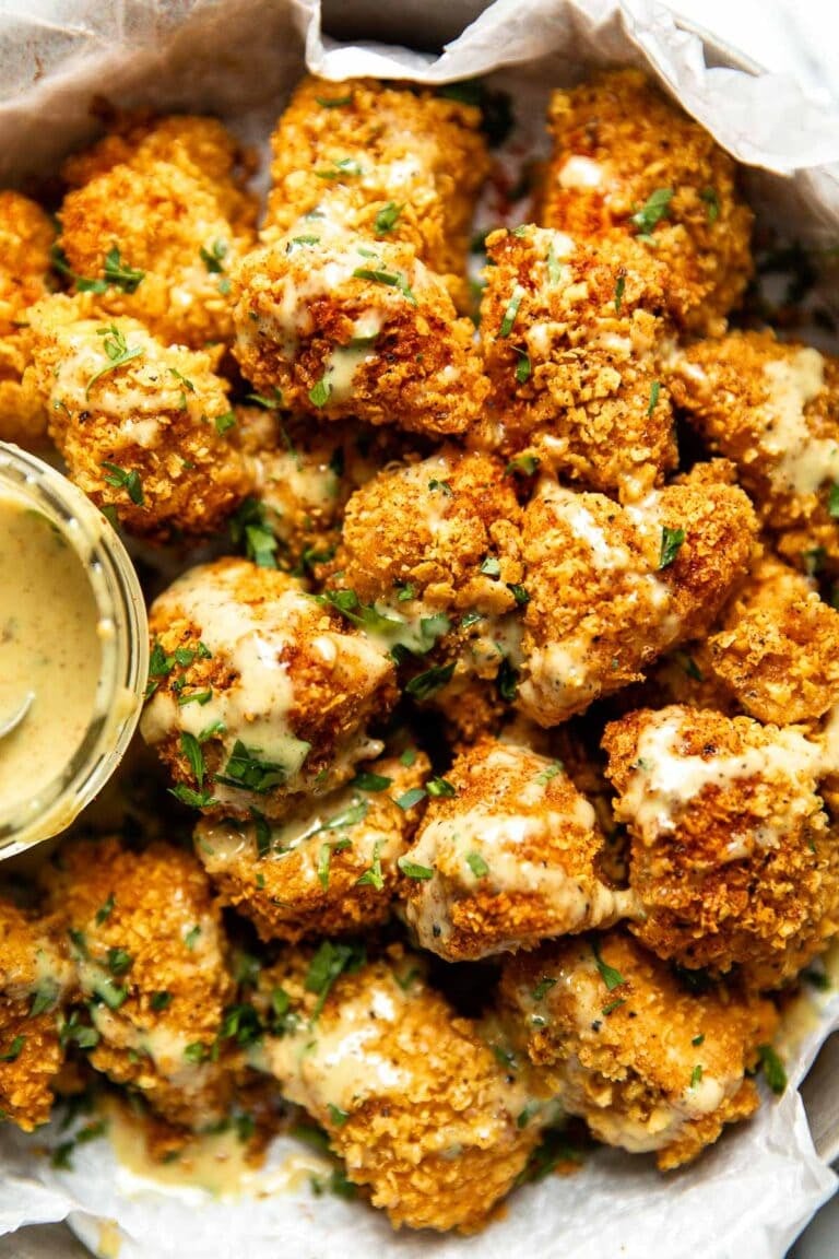 Overhead view of a bowl of homemade chicken nuggets drizzled with honey mustard sauce. 