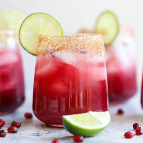 A pomegranate margarita with a lime wheel and sugared rim.