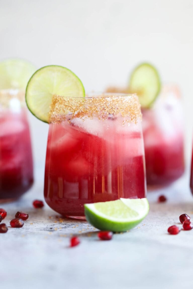Close up view of a pomegranate margarita garnished with a lime.