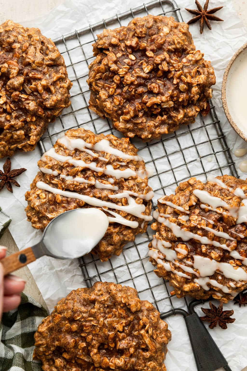 Overhead view of chai spice protein breakfast cookies on a cooling rack being drizzled with white icing. 