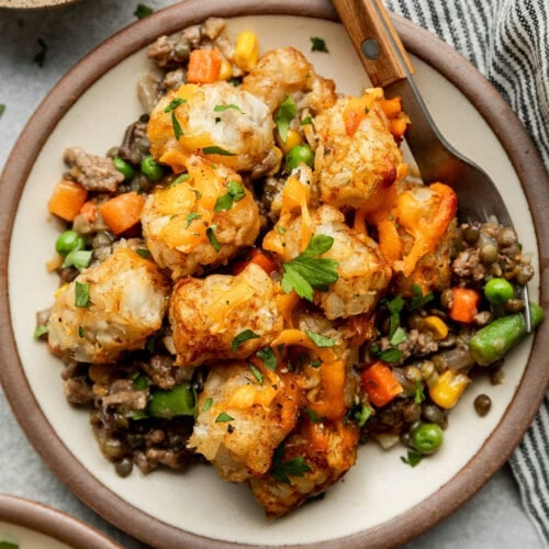 Overhead view stone plate with serving of tater tot casserole, fork on side of plate