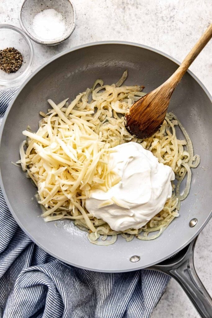 Skillet with sautéed onions, sour cream and shredded cheese.