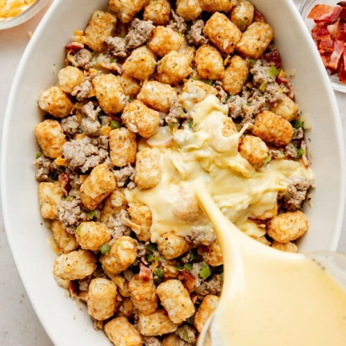 Whisked eggs and milk being poured over tater tot breakfast casserole