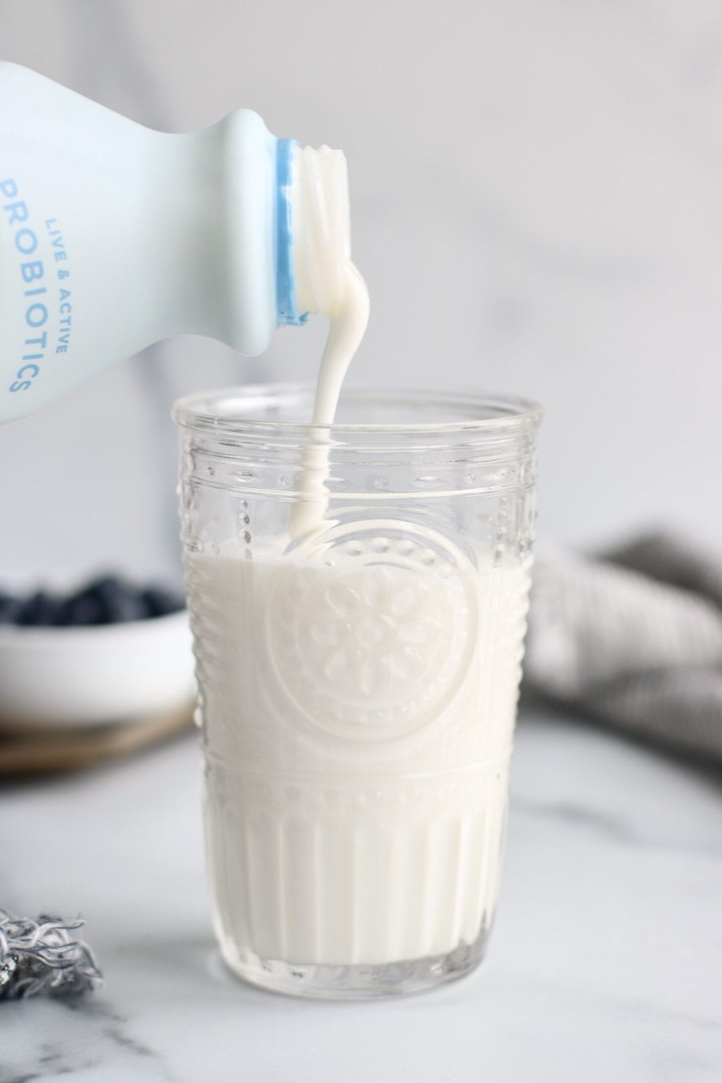 Close up view of a glass being filled with white kefir. 