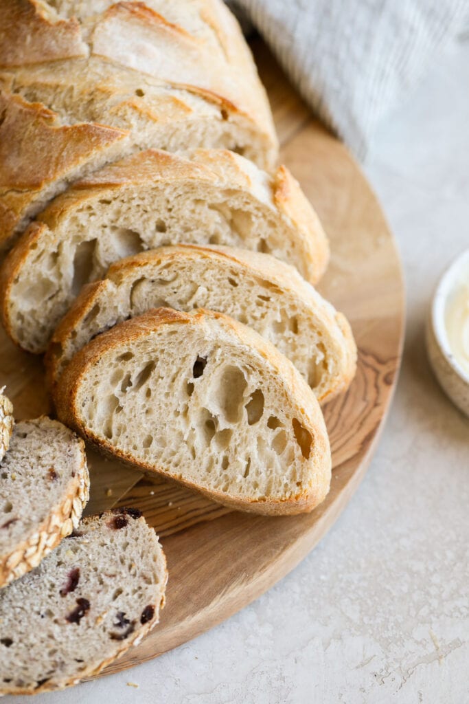 Close up view of sliced sourdough bread on a wooden cutting board.