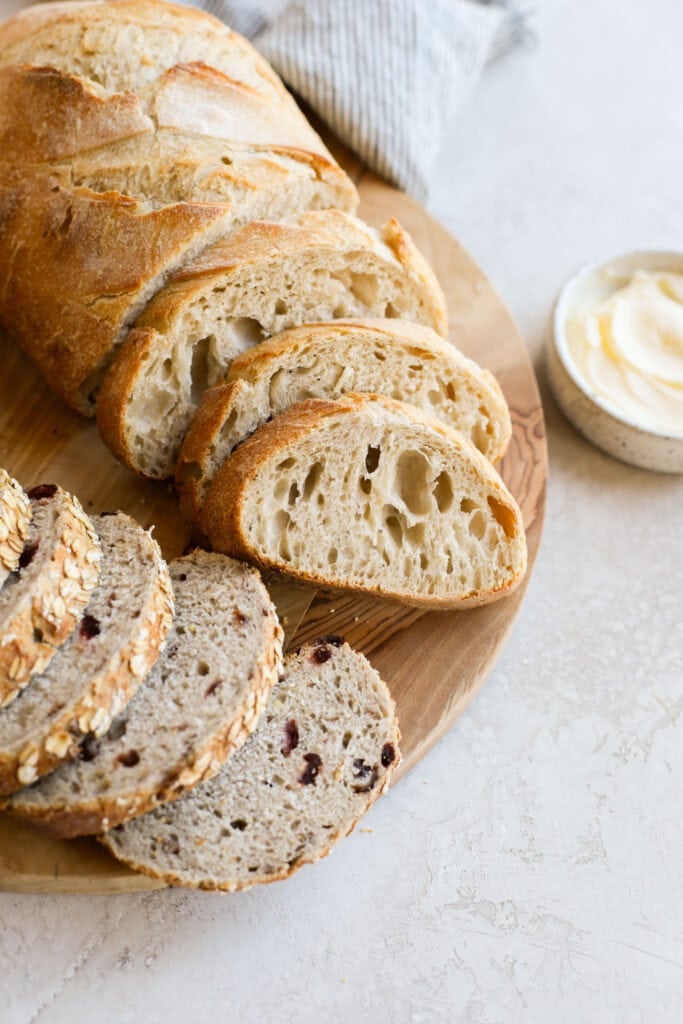 Close up view of sliced sourdough bread on a wooden cutting board.