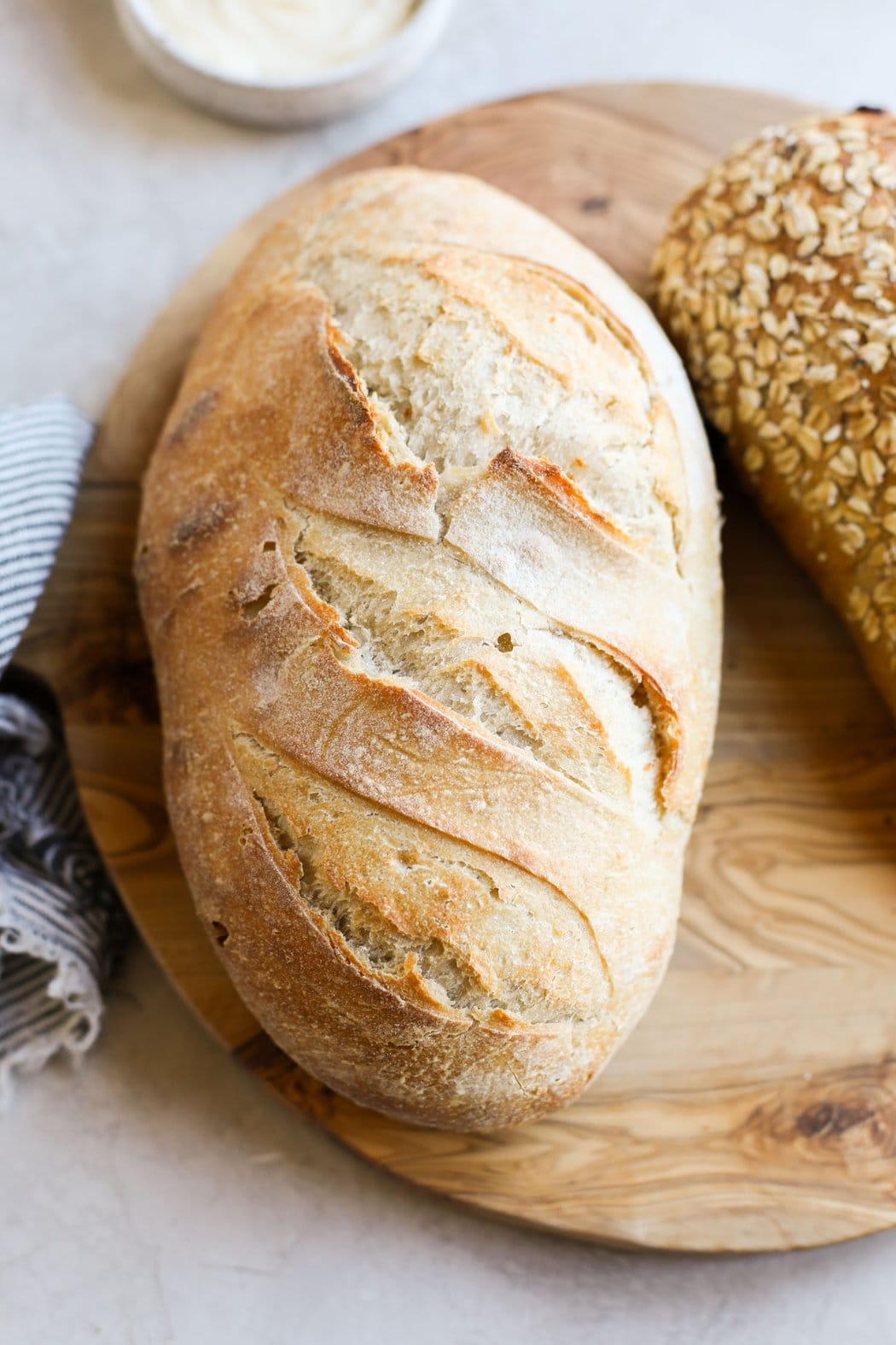 Close up view of a loaf of fresh sourdough bread on a wooden cutting board.