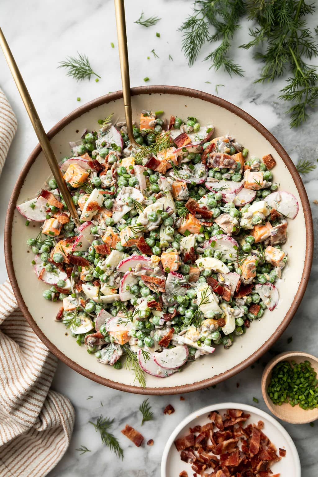A white bowl filled with Creamy Pea Salad topped with fresh dill
