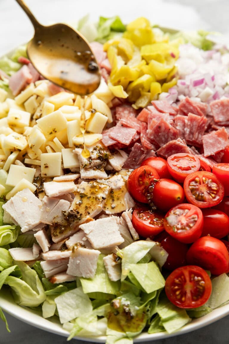 Overhead view of a salad topped with chopped tomatoes, lettuce, cheese, and deli turkey.